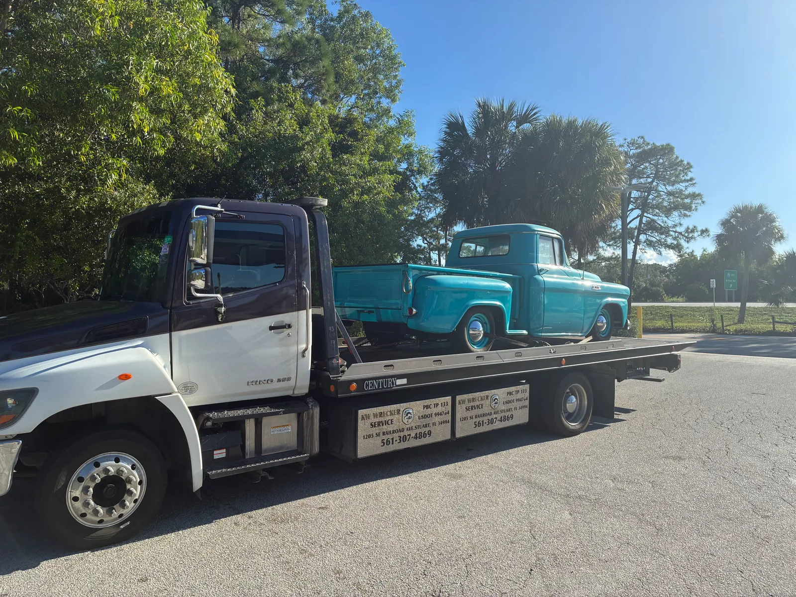 KW Wrecker Service flatbed transporting a restored turquoise 1950s classic pickup truck