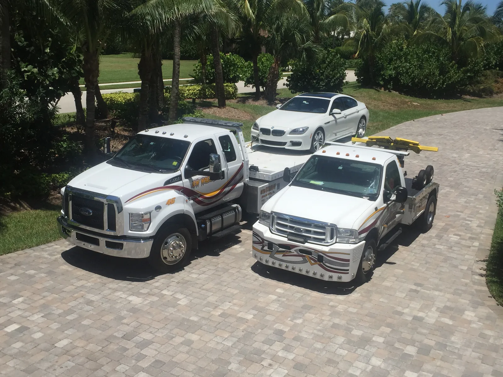 KW Wrecker Service flatbed and light-duty wrecker transporting a luxury BMW sedan